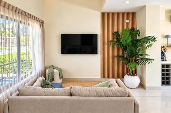 Sala con sofá, pantalla de televisión, pared de listones de madera y una palmera